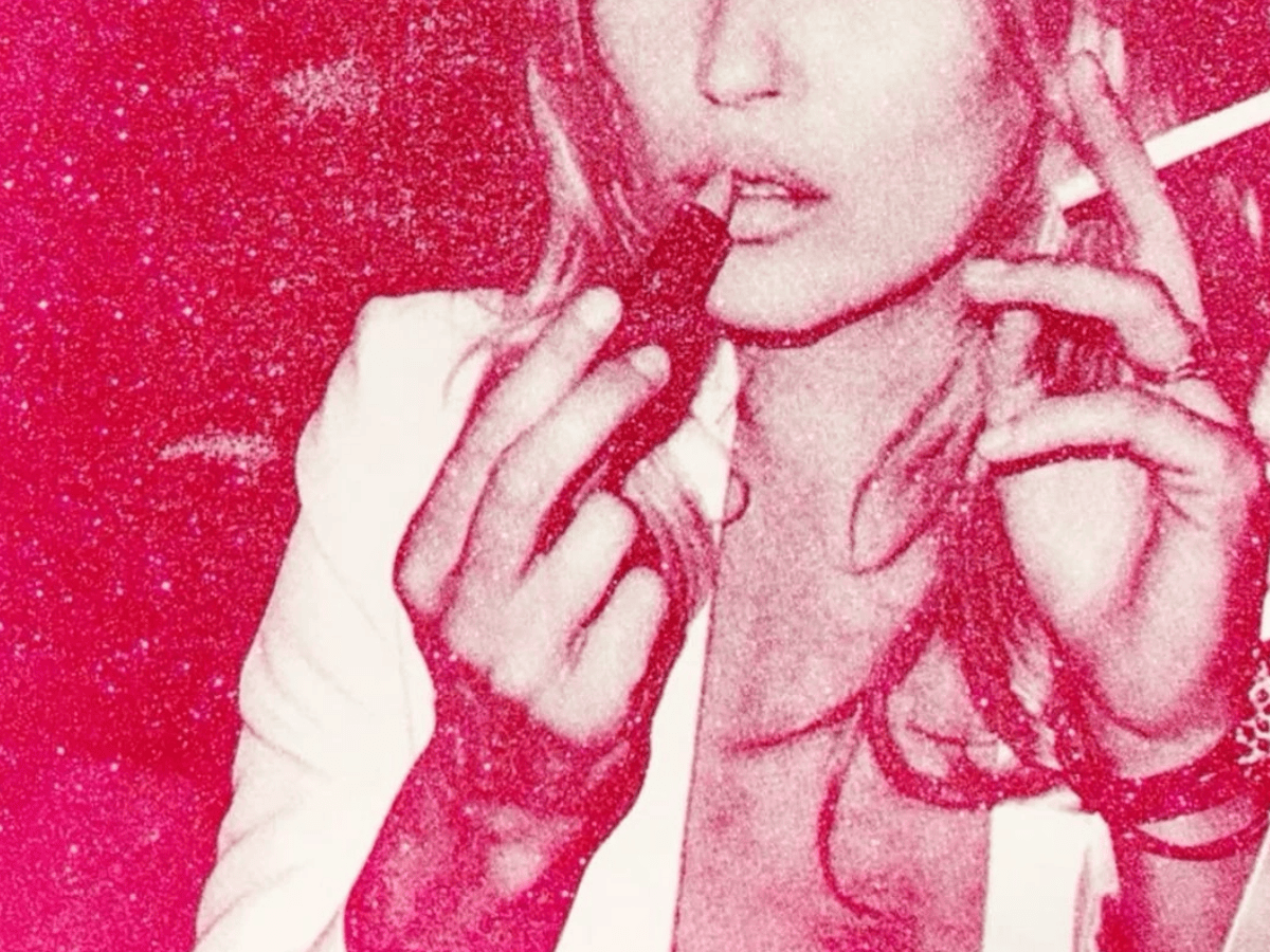 Grainy crimson and pink duotone photo of a woman holding a lipstick to her lips in one hand and a pre-roll in the other, against a glittery pink background.